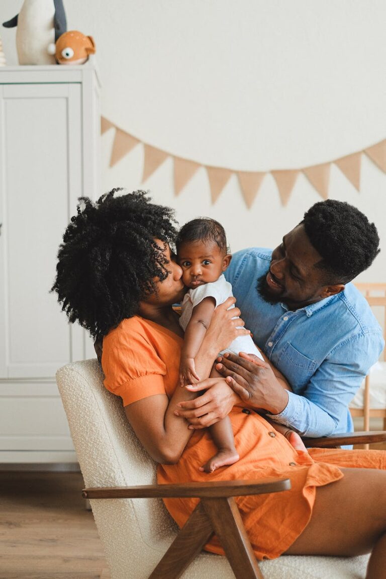 woman kissing a baby beside a man