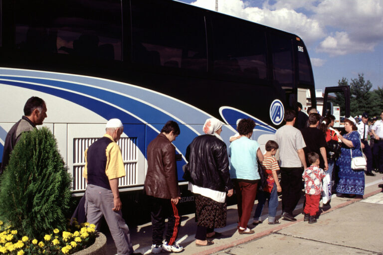 Kosavar refugees load onto a bus enroute to Fort Dix, New Jersey. A Tower Air 747 (not shown) loaded with Kosovar refugees landed at McGuire Air Force Base, New Jersey, on May 5, 1999. This mission is in direct support of Operation Sustain Hope.