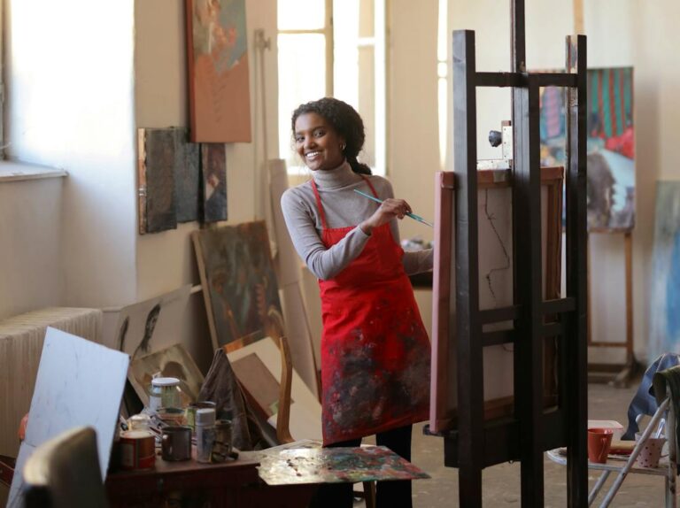happy artist drawing on easel in workplace