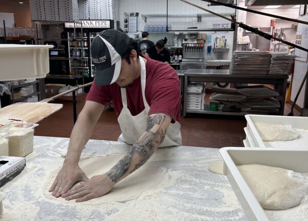 chef flattening pizza dough at Frank Pepe